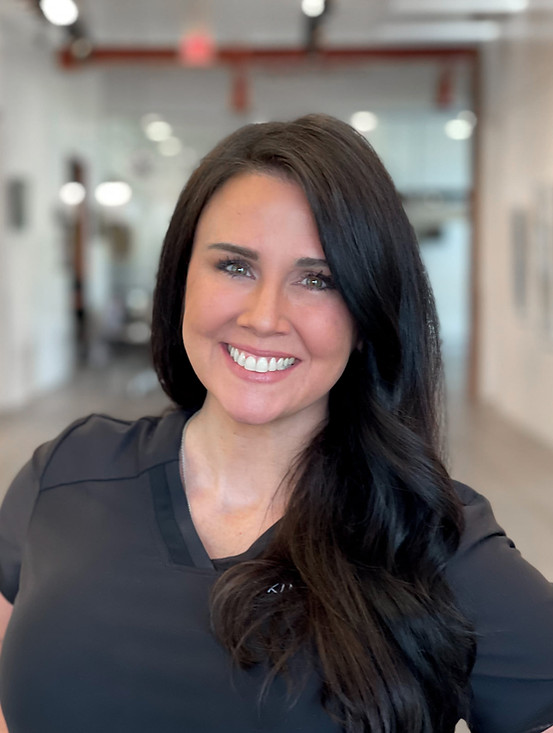 Portrait of Dana Mayes, smiling and wearing a black uniform, standing in a well-lit hallway.