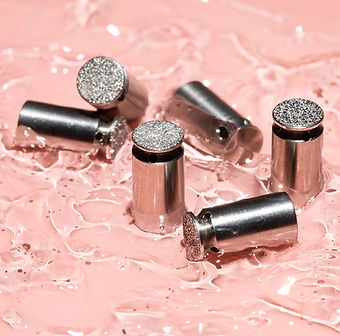 Close-up of microdermabrasion tips on a pink surface.