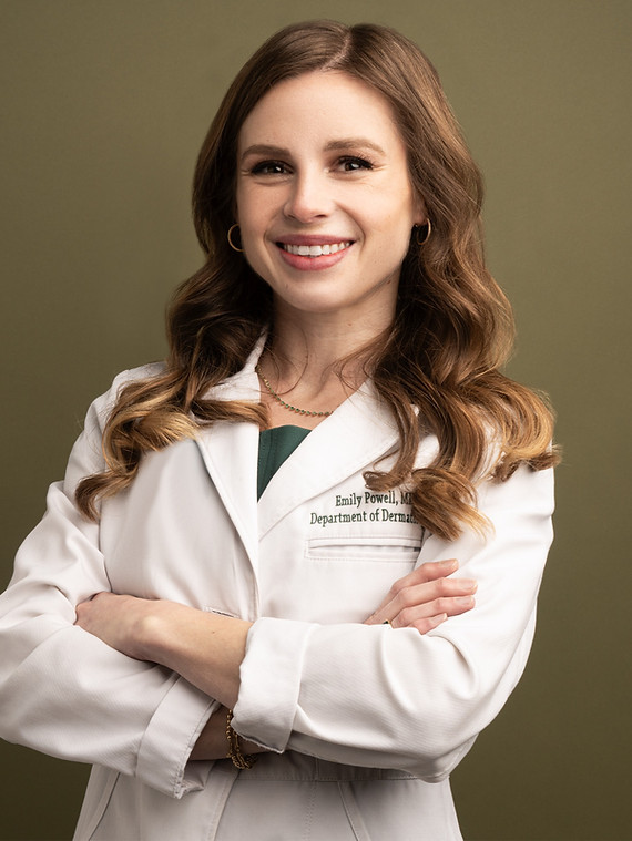 Dr. Emily Powell in a white coat smiling with arms crossed.