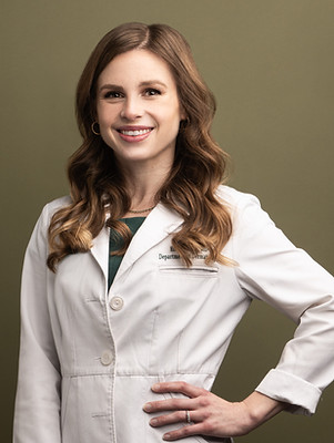 Portrait of Dr. Emily Powell, smiling and wearing a white lab coat, standing against a plain background.